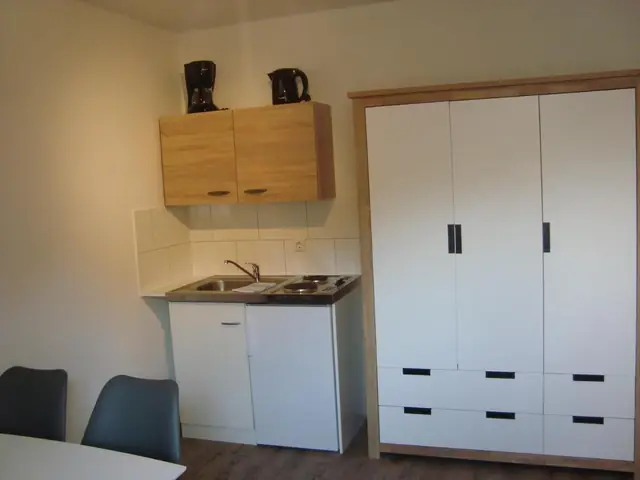 Küche mit Wasserkocher, Kaffeemaschine und weißem Schrank