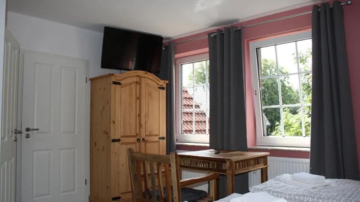 Wohnraum des Apartments mit Fenstern, Holzschrank und TV